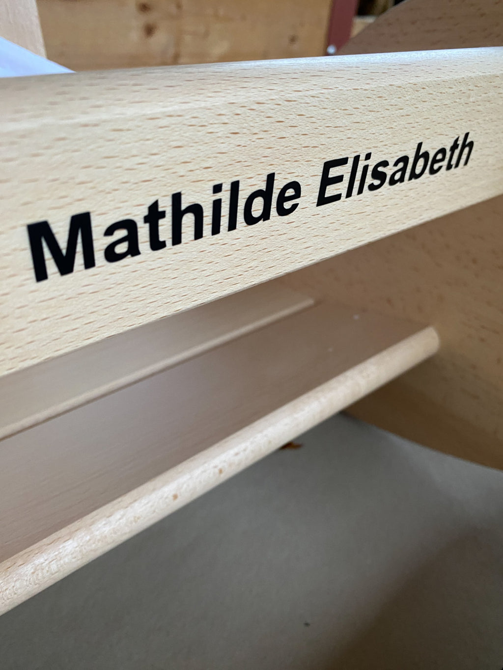 Langer Name in schlichter Schrift auf einer Schaukelschnecke aus Buchenholz